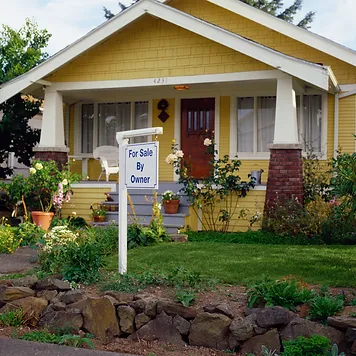 A yellow house with a sign in front of it